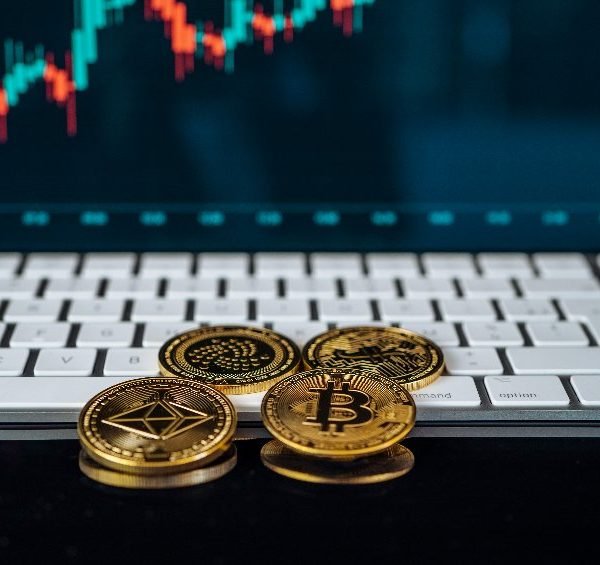 Trois bitcoins sur un clavier à côté d'un graphique boursier.