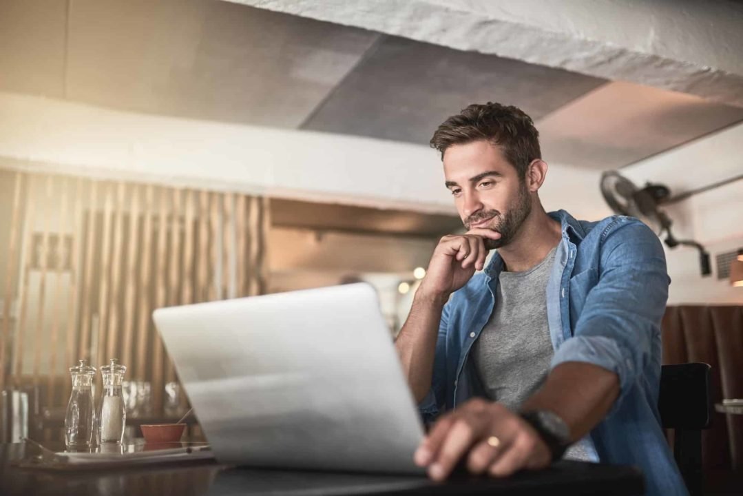 Connected to a day of productivity. Shot of a handsome young man using a laptop in a coffee shop.