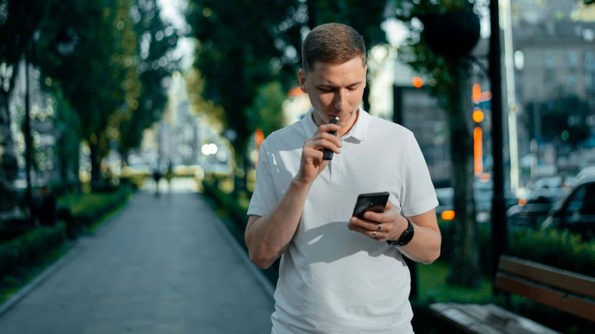 Un homme fume une cigarette électrique dans la rue