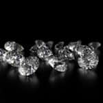 Une collection de diamants taille ovale dispersés sur une surface noire réfléchissante.