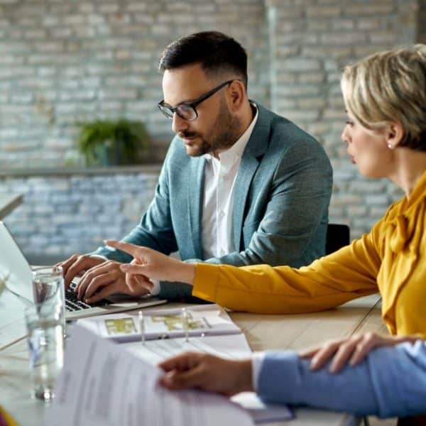 Agent immobilier utilisant un ordinateur portable lors d'une réunion avec un couple au bureau.