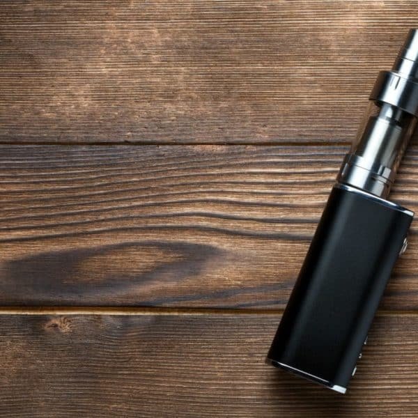 Un Appareil à Vapotage Noir Repose Sur Une Surface En Bois.