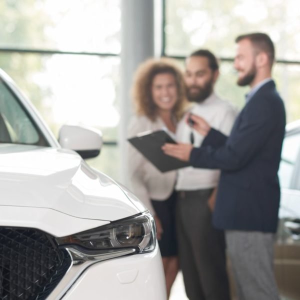 Car dealer discussing purchase of car with clients
