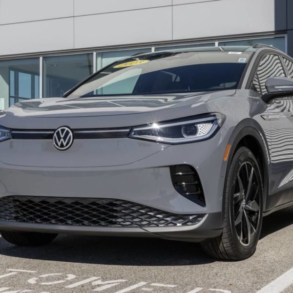 Un Suv électrique Volkswagen Gris Garé Devant Un Bâtiment, Avec Un Autocollant Jaune Visible Sur Le Pare Brise.