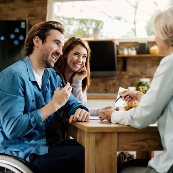 Young happy couple talking to insurance agent while using touchpad on a meeting.