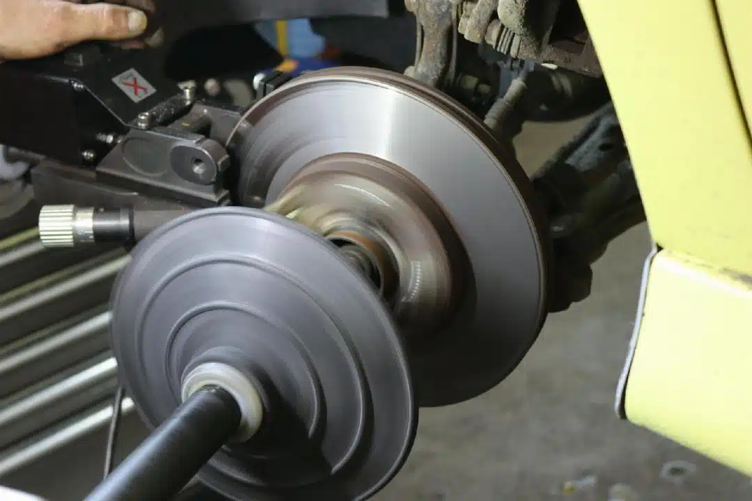 Une Machine Est Utilisée Pour Refaire La Surface D'un Disque De Frein De Voiture, Le Disque Tournant Rapidement Lorsqu'il Est Fixé à Un Véhicule Jaune.