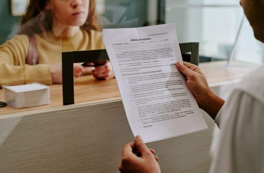 Une Personne Remet Un Document à Une Femme Debout à Un Comptoir De Service, Qui Tient Sa Carte D'identité.