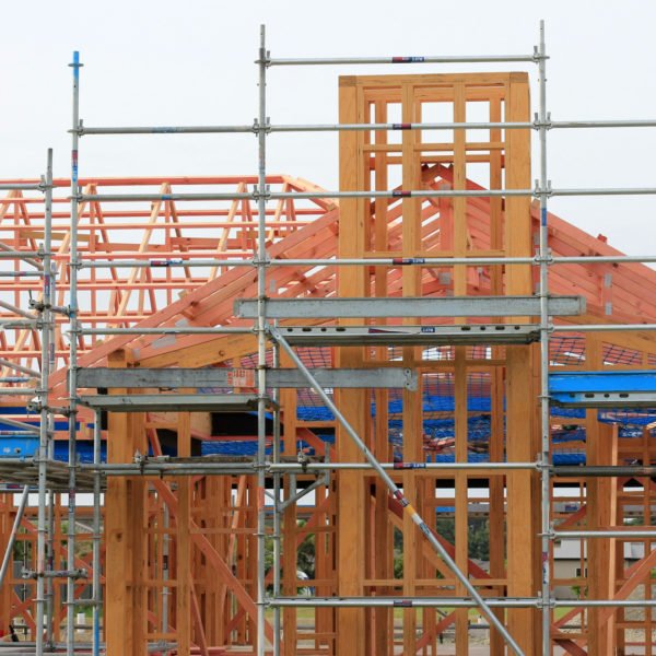 Charpente De Maison En Bois En Cours De Construction, Avec échafaudages Et Poutres Structurelles Visibles, Sans Murs Ni Toit Encore Achevés.