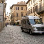 Camping-car argenté sur rue pavée d'une ville historique italienne, avec un panneau ZTL indiquant des restrictions horaires.