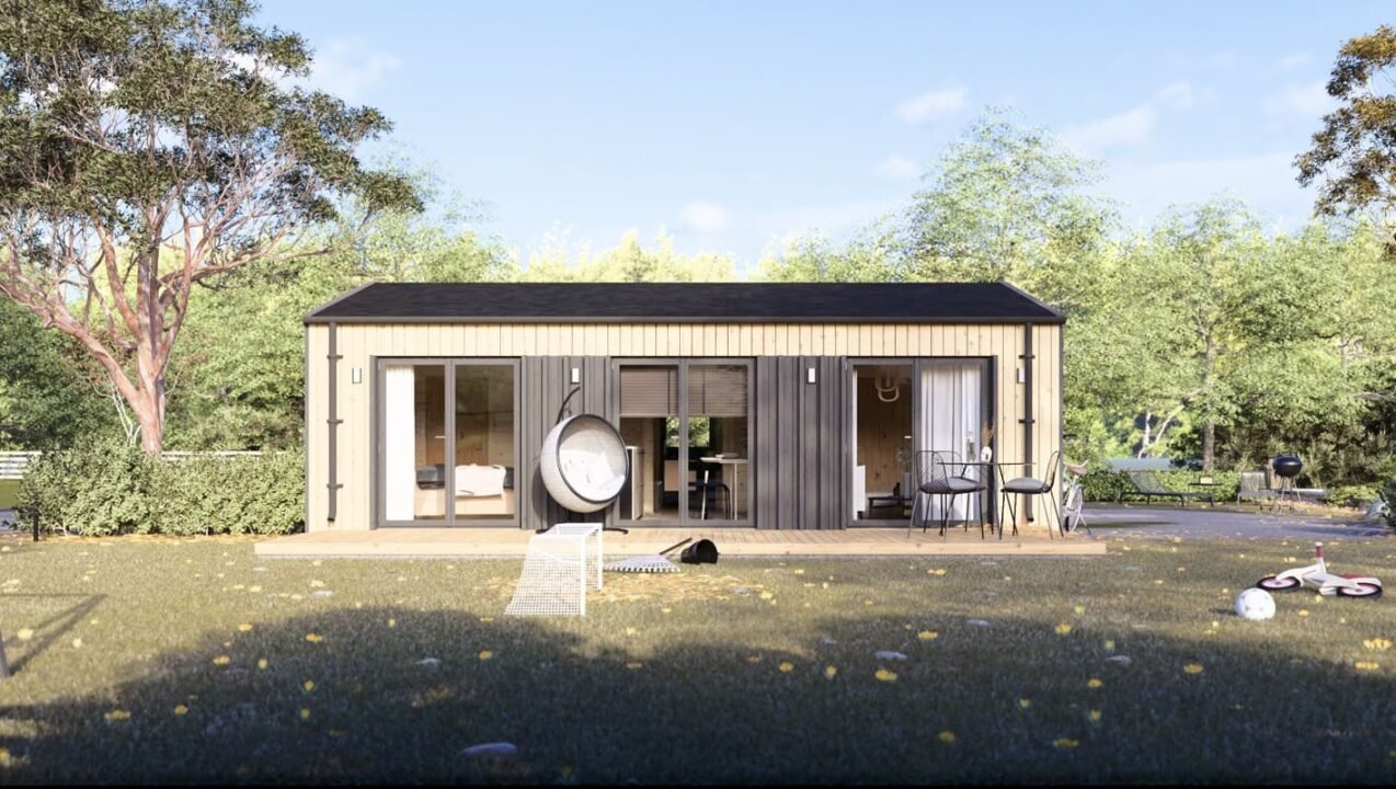 Petite Maison Moderne De Plain Pied Avec Bardage En Bois, Grandes Portes Vitrées, Petit Porche, Meubles De Terrasse Et Jouets D'enfants éparpillés Sur Un Terrain Herbeux, Entouré D'arbres.